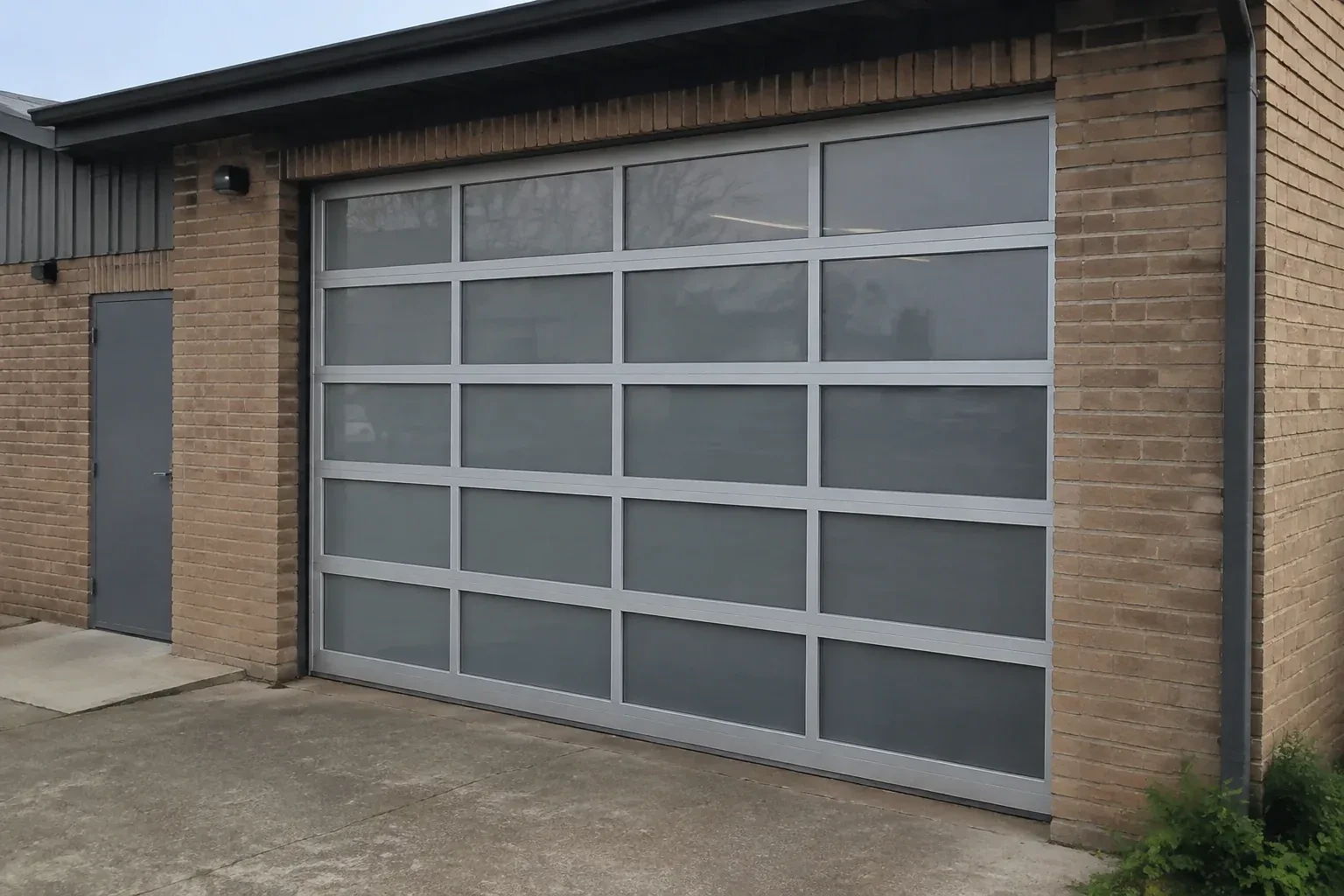 Closed glazed sectional door in a grey metal frame at a brick workshop. — Full-View Glass Garage Door Installation, Markham